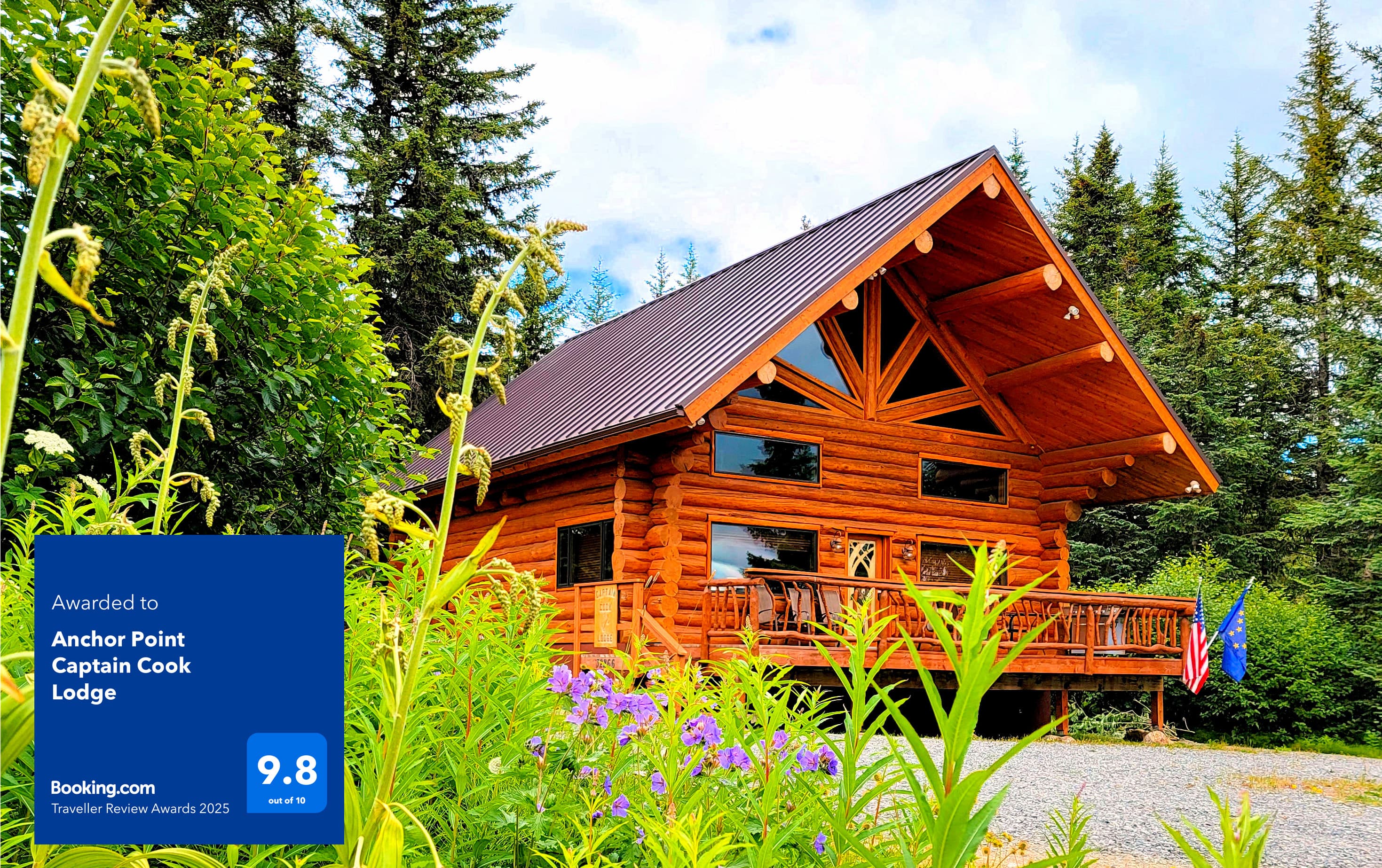 Captain Cook Lodge two-story log cabin nestled amidst lush greenery and tall pine trees under a partly cloudy sky.