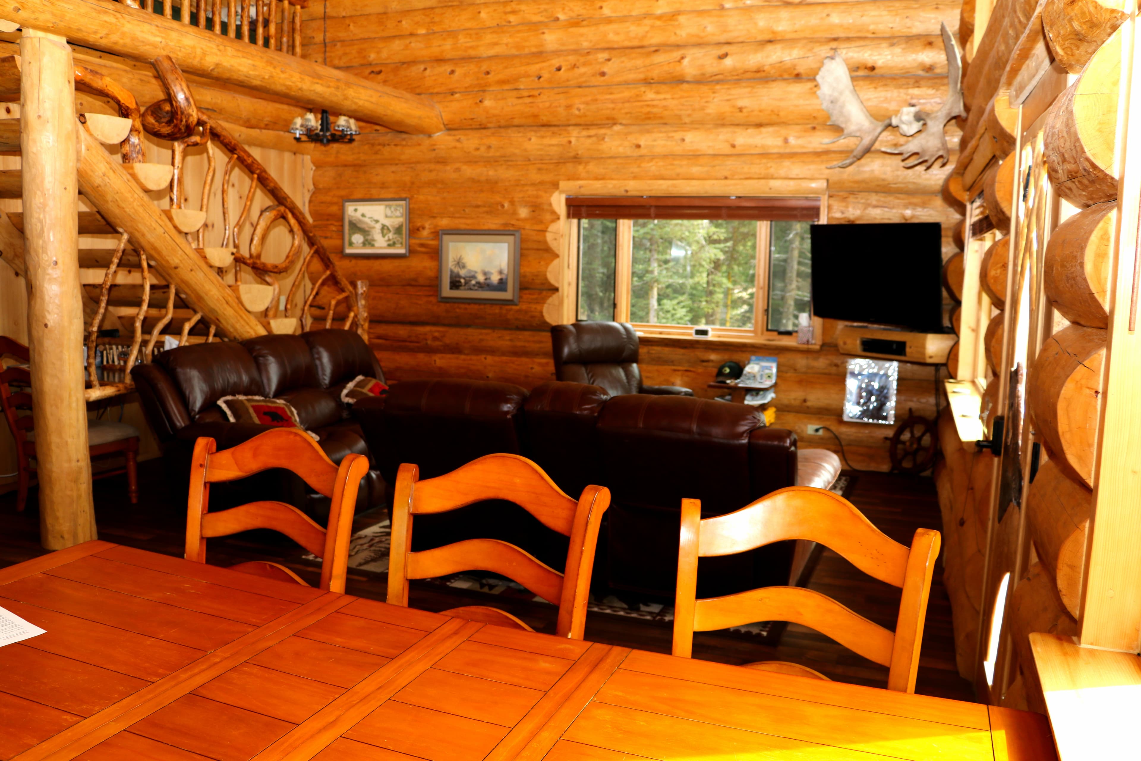 First Floor View 5 - Dining area in foreground with sitting area and TV in background as well as stairs leading to loft.