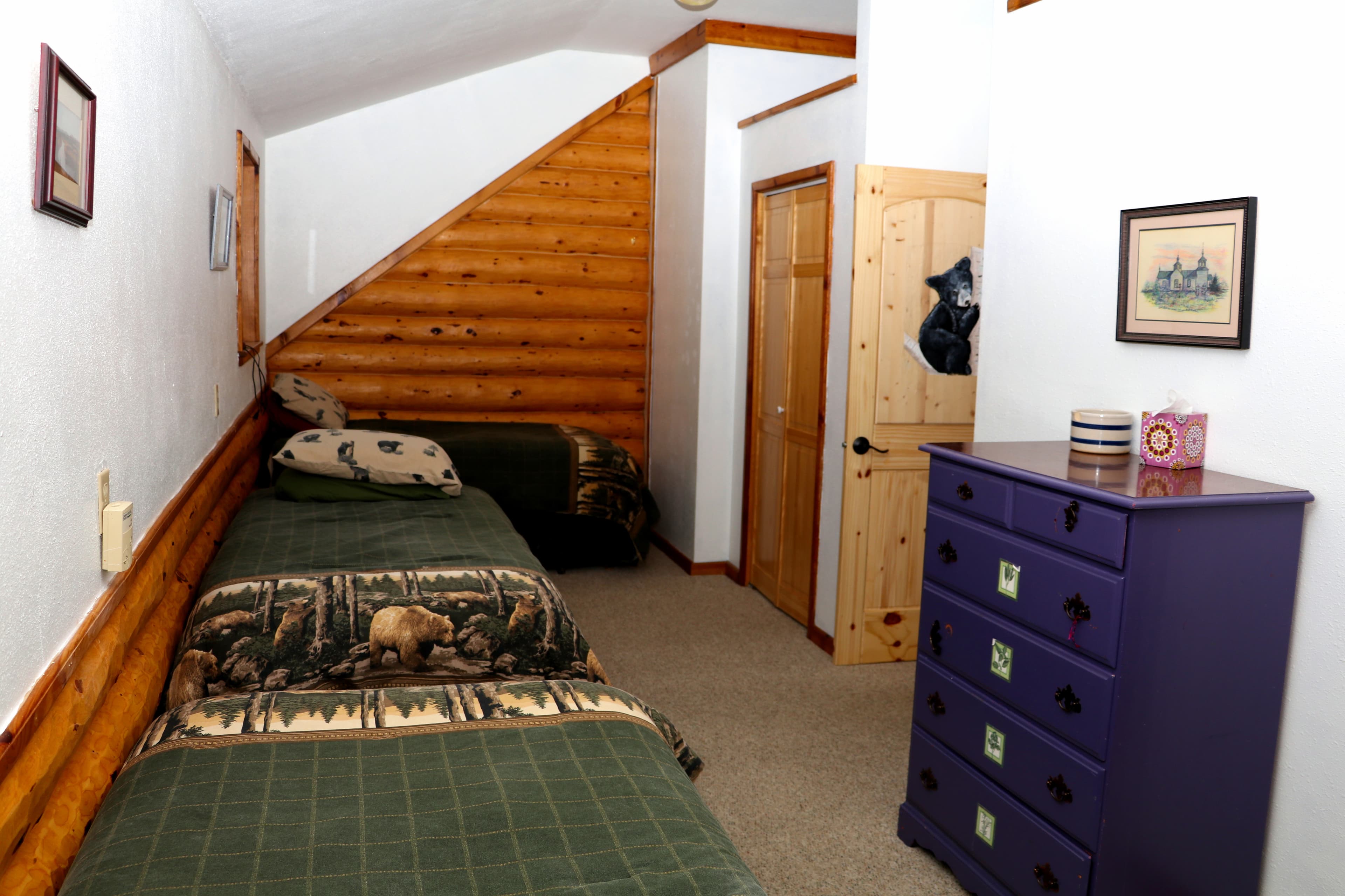 2nd floor bedroom with twin bedrooms, dresser, and sloped ceilings.