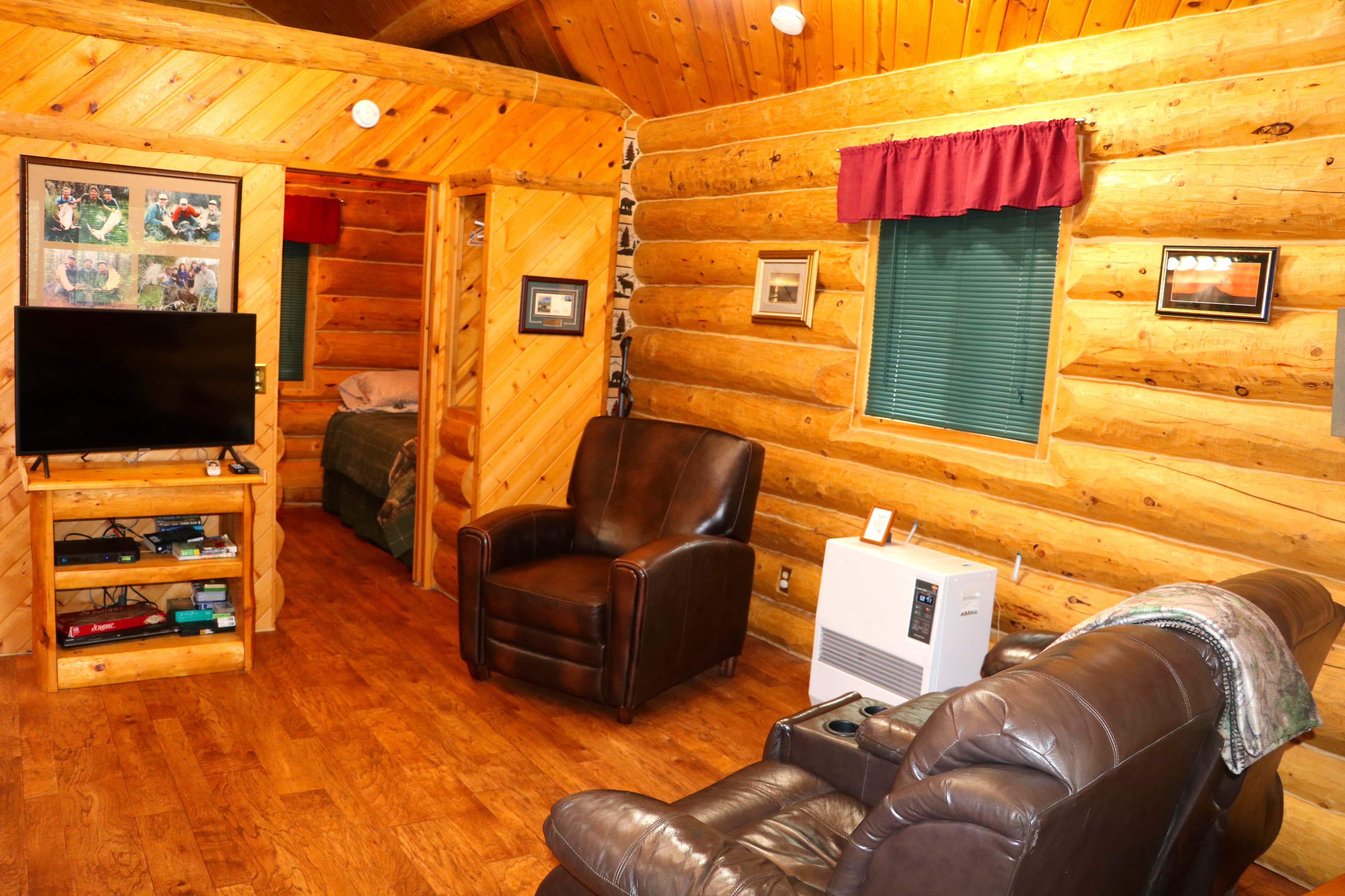 The Moose Cabin den with rich brown leather furniture, log walls, and a flat-screen